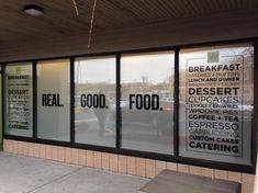 the front window of a restaurant with signs on it's windows and cars parked in the parking lot