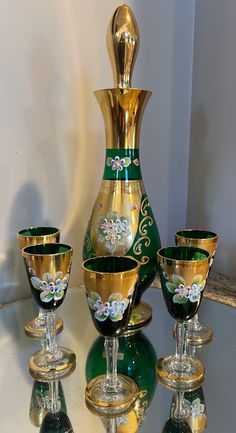 a set of four wine glasses and a vase on a table with other glassware