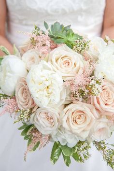 a bride holding a bouquet of white and pink flowers