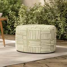 a green and white ottoman sitting on top of a rug next to a wooden table