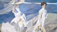 two women in white dresses walking on the beach