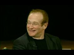 a man with glasses and a black shirt is sitting in front of a dark background