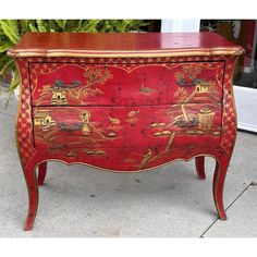 a red and gold painted chest on the sidewalk