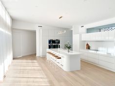 a large kitchen with white cabinets and counter tops, along with an island in the middle