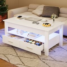 a white coffee table with drawers underneath it and a laptop computer on the top shelf