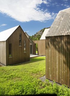 two wooden buildings sitting next to each other on top of a grass covered field with trees in the background