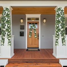 the front porch is decorated with white flowers and greenery, along with wooden steps