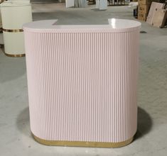 a large pink and gold pedestal in the middle of a warehouse with other items behind it