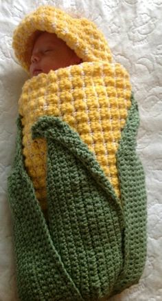 a newborn baby wrapped in a green and yellow blanket