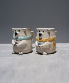 two ceramic bears with scarves and scarfs on their heads are sitting side by side