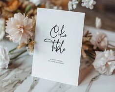 a white card with the words one table written on it next to some pink flowers