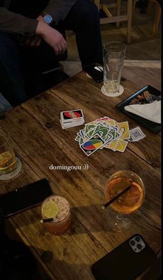 there are some drinks on the table with cards in front of them and two people sitting down