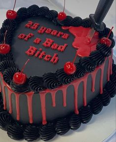 a black and red birthday cake with cherries on it