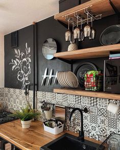 a kitchen with black and white tiles on the wall, wooden counter tops and shelves