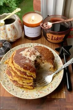 a stack of pancakes sitting on top of a white plate next to a cup of coffee