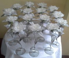 there are many wine glasses that have flowers in them on the tablecloth with white cloth