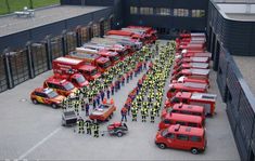 a large group of people standing in front of many red trucks