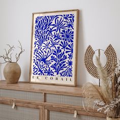 a blue and white art piece sitting on top of a wooden shelf next to vases