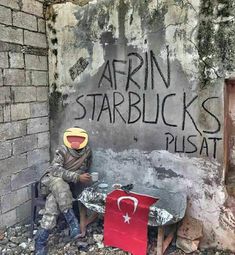 a man sitting in front of a wall with graffiti on it