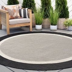 a black and white rug sitting on top of a wooden floor next to potted plants