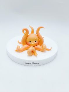 an orange octopus figurine sitting on top of a white plate with its eyes closed