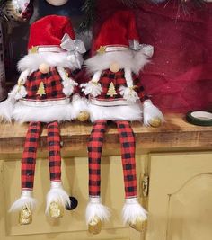 two christmas gnomes sitting on top of a kitchen counter next to each other in red and black checkered outfits