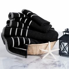 black towels in a basket next to a lantern and starfish