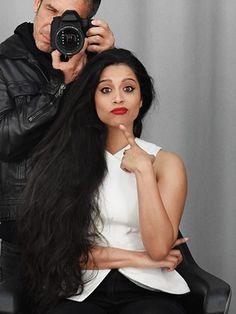 a man taking a photo of a woman's long hair with a digital camera