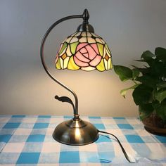 a lamp that is on top of a table next to a potted plant and a blue checkered table cloth