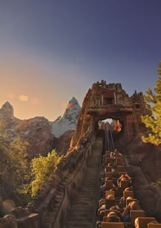 people are sitting on the steps leading up to an old castle like structure with mountains in the background