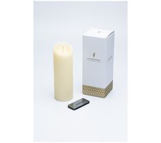 a white candle next to a box and remote control