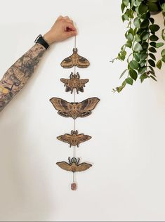 a person holding up a wall hanging with moths on it's sides and hands