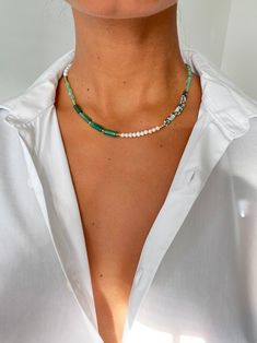 a woman wearing a white shirt and a multicolored beaded necklace on her chest