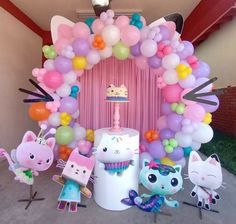 a bunch of balloons that are in front of a cake and cupcake on a table