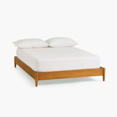 a bed with white sheets and pillows on top of it's headboard, against a white background