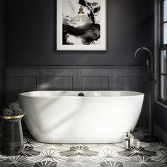 a white bath tub sitting in a bathroom next to a window with a painting on the wall