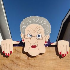 an old woman's face is painted on the side of a wooden fence