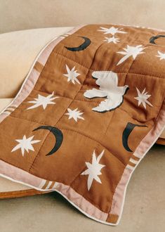 a brown and white blanket on top of a couch next to a pillow with stars