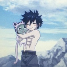 a young man holding a stuffed animal in his arms while standing on top of a mountain