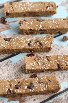 four bars with nuts and dried cranberries sitting on top of a wooden table