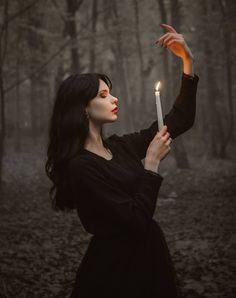 a woman holding a candle in the woods