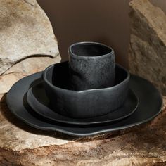 a black plate with two cups and saucers sitting on top of it next to some rocks