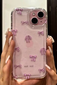 a woman holding up a pink phone case with bows on the front and back cover