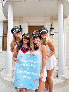 three beautiful women standing next to each other in front of a building holding a sign