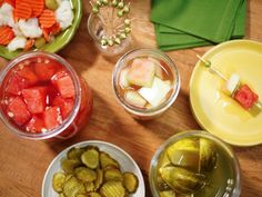 there are many different types of vegetables in bowls on the table, including pickles and watermelon