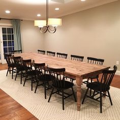 a large wooden table with black chairs in a living room next to a door and window