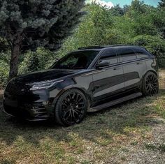 a black range rover parked in front of some trees