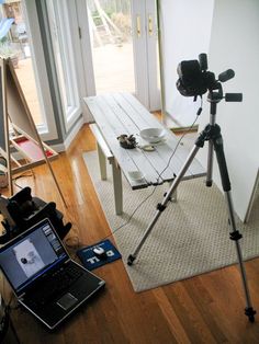 a laptop computer sitting on top of a wooden floor next to a camera and tripod