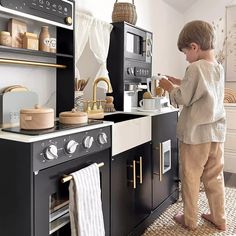 a little boy that is standing in front of a stove