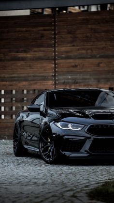 a black car parked in front of a wooden fence